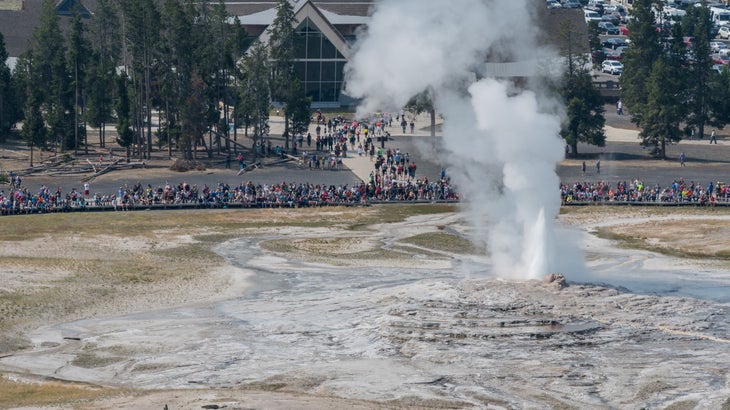 A massive crowd gathers to watch Old Faithful in Yellowstone National Park.