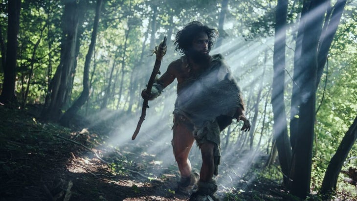 A prehistoric man hunts with a spear in the forest