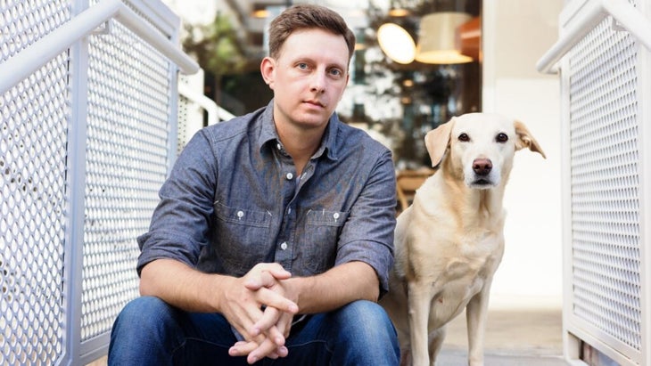 A shot of the author sitting on his porch next to his white dog