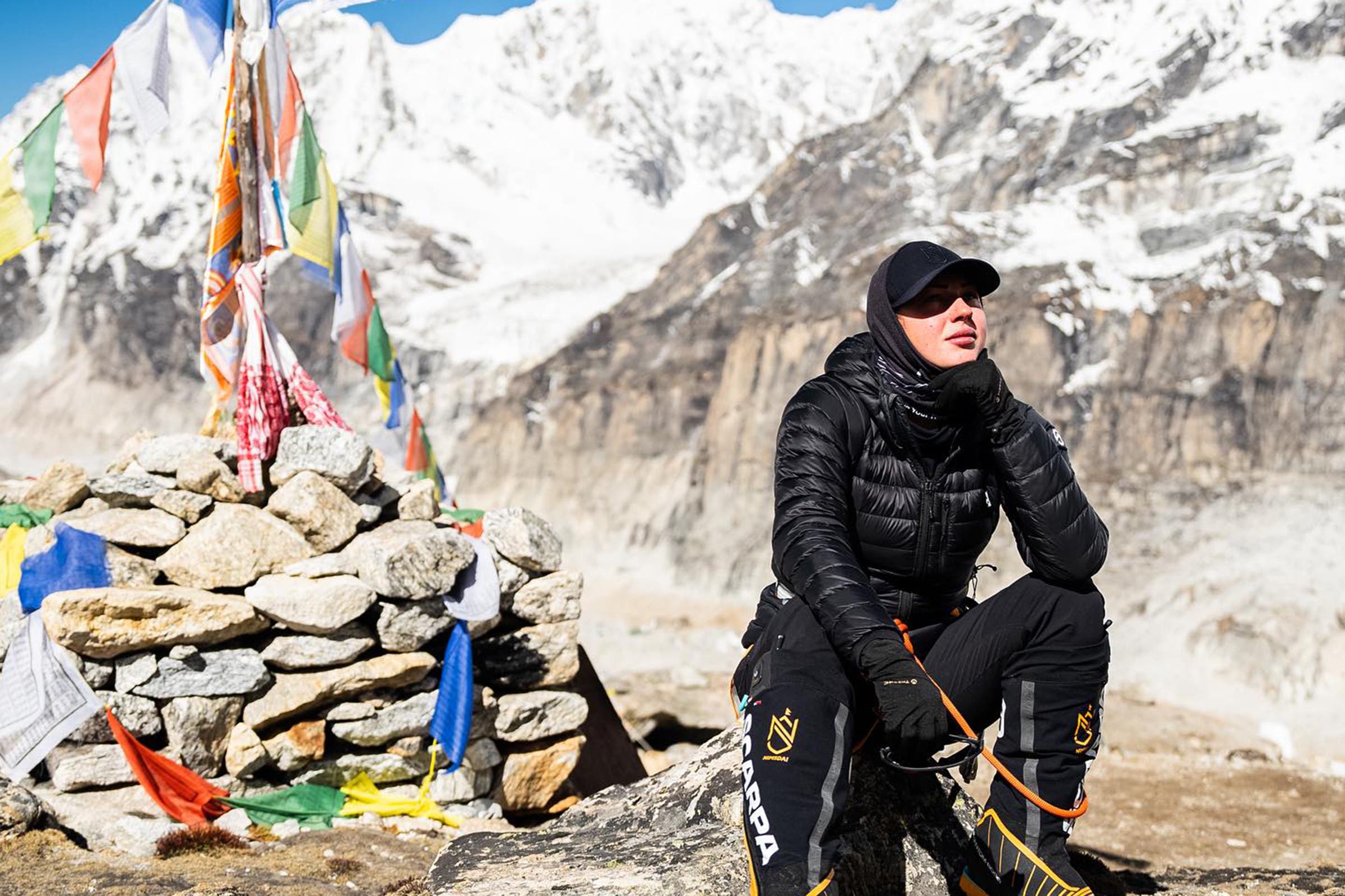 A woman sitting next to a cairn