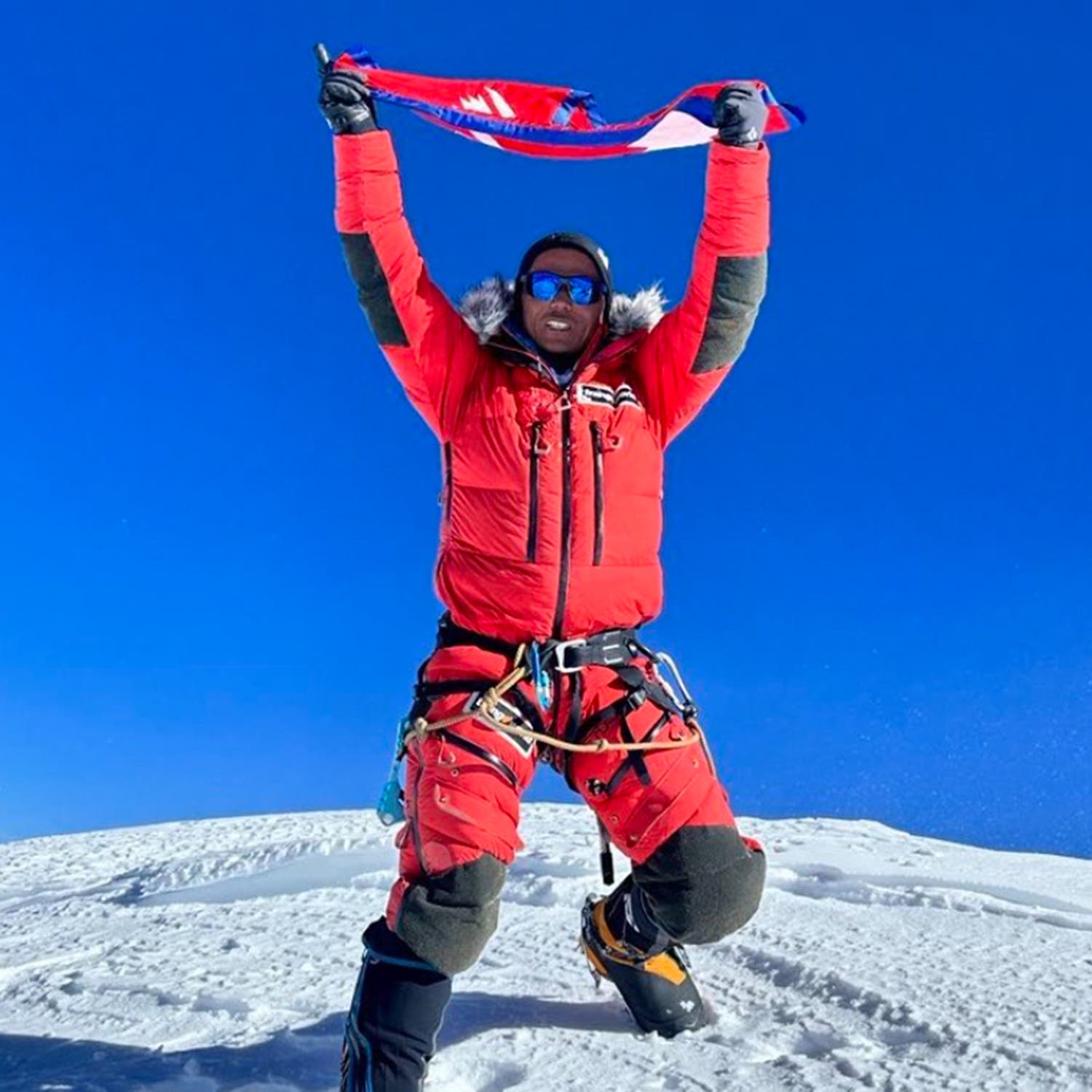 A climber holding on flag on a mountain's summit