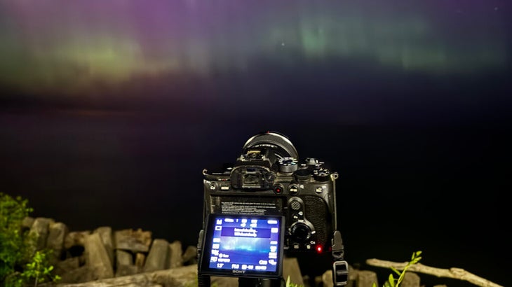 A Sony camera is set up to capture the northern lights, tilted at a sky full of colorful ribbons.