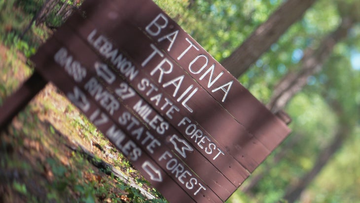 A sign on the Batona Trail in the Pine Barrens highlights mileages to New Jersey state forests.