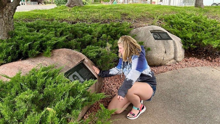 young girl reads memorial plaques at Storm King