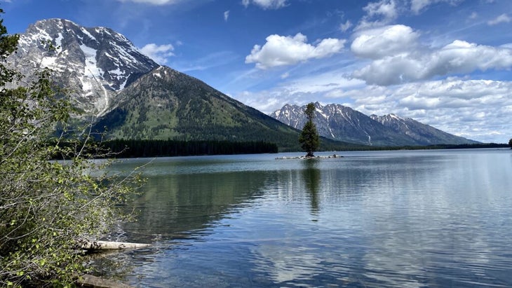 Two mountains lightly covered in snow reflect onto the waters of String Lake, Wyoming, in Grand Teton National Park.