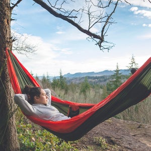 a woman relaxing in a red hammock (training less!) in the mountains