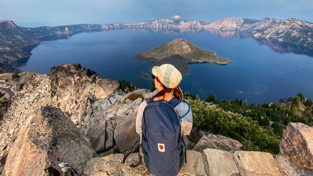 The author sits atop Watchman Lookout, in Crater Lake National Park, with an incredible view of the entire lake.