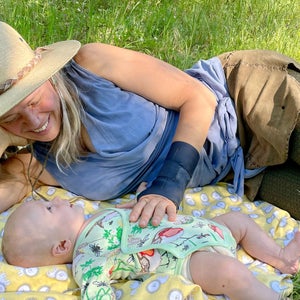 Woniya Thibeault lying on a blanket on the grass next to her infant son.