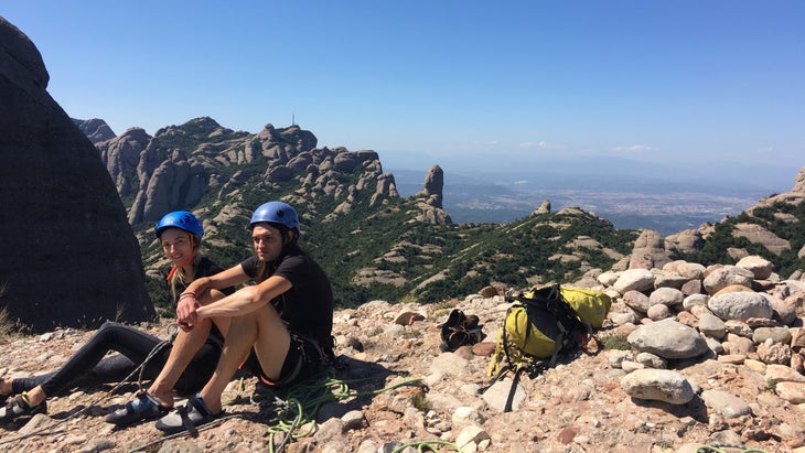Olivia and her husband sitting with helmets and ropes having just climbed a multipitch route in Spain.