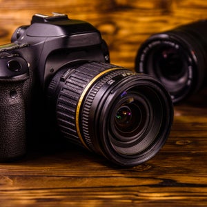 Closeup of unbranded black digital camera and lenses on wooden table