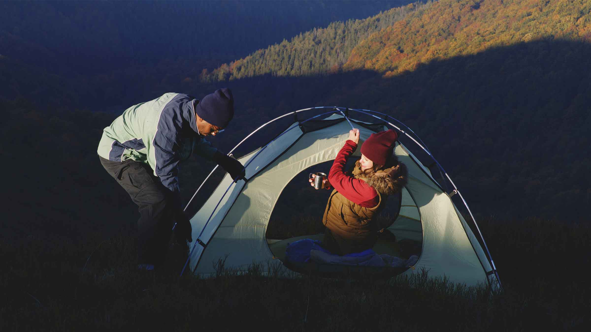 A man sets up a tent early in the morning.