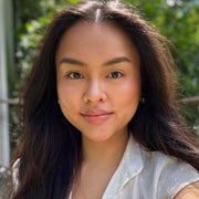 Isabella Rosario sitting in front of a green bush