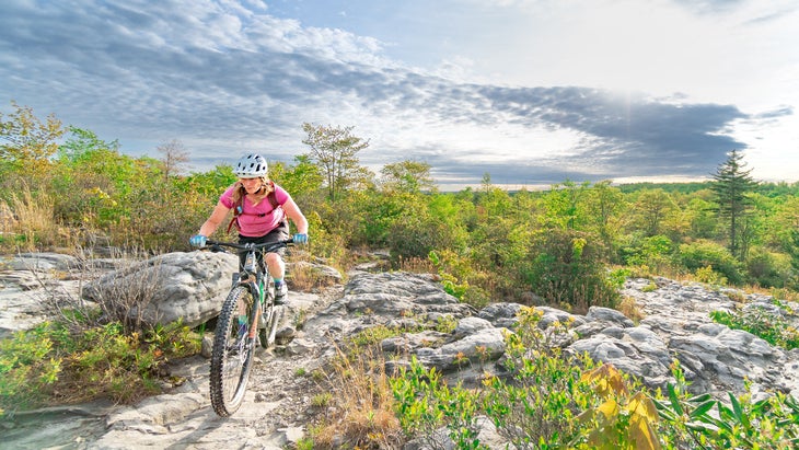 woman rides mountain bike over rocks in West Virginia