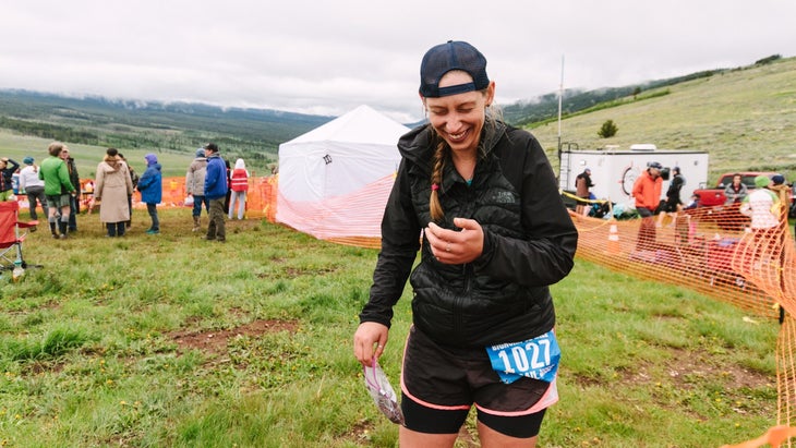 a woman laughing at an aid station at a running race