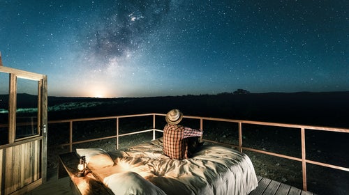 sitting in bed outdoors under a starry sky