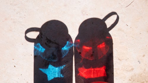 Photo of two nalgene bottles with the reflection of a flag—one is red, one is blue