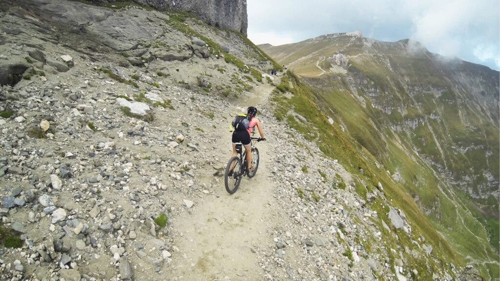 A woman rides her mountain bike on a trail along a massively steep hillside in central Romania near Mount Omu.