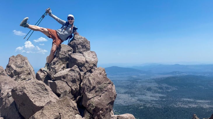 The author celebrating her arrival at Lassen’s summit atop a mound boulders, with a panorama spread out below.