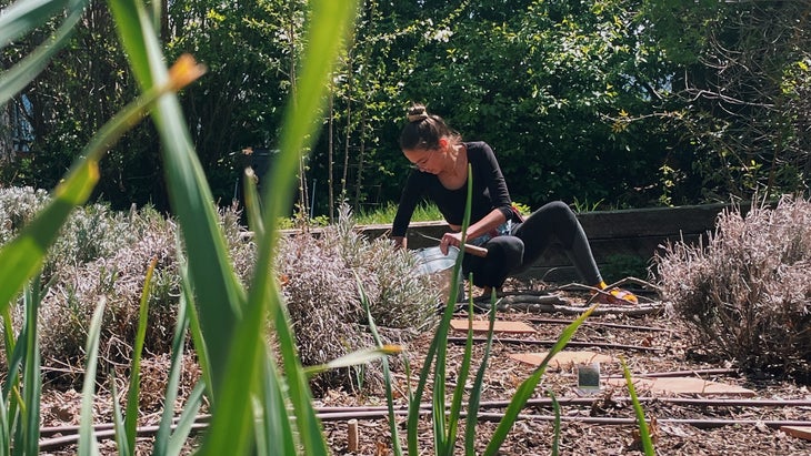 woman crouched in garden with silver bucket