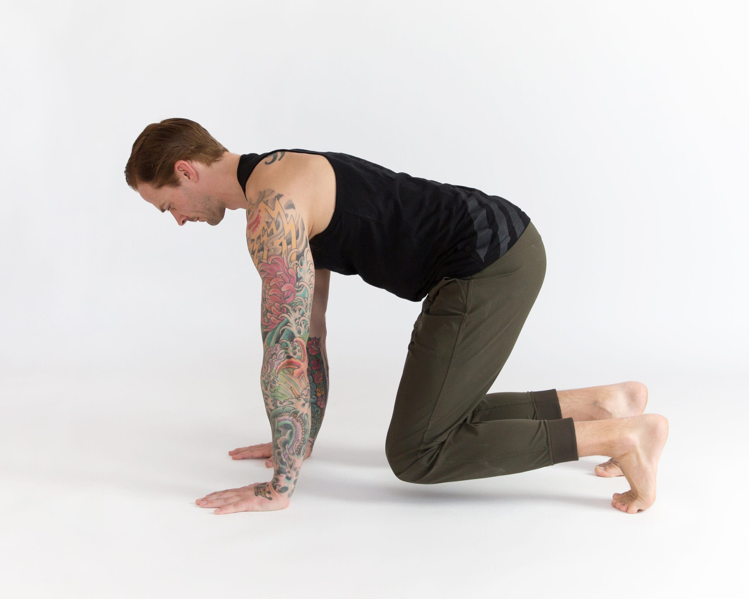 Man in beast. He is on all fours with knees hovering over ground.