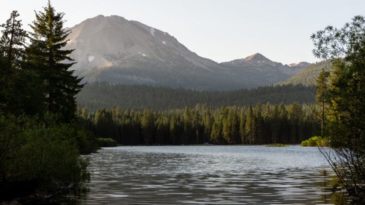 Lassen Peak, the surrounding forest, and a lake at sunrise