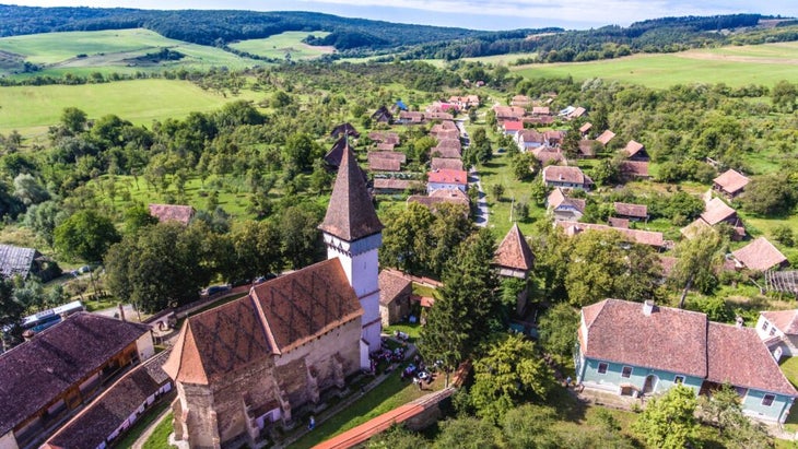 An aerial view of Mesendorf, a traditional saxon village in Transylvania, Romania, with a fortified church at its center.