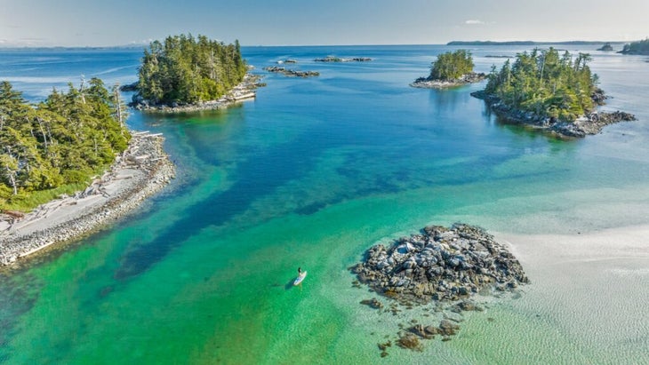 A woman stand-up-paddleboards the islet-filled bay in front of British Columbia’s Shearwater Resort.