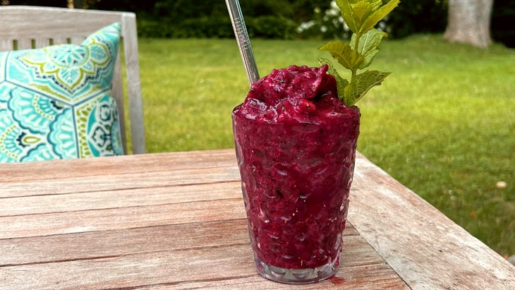 Stay cool with a strawberry slushy, pictured on a wooden table with grass in background