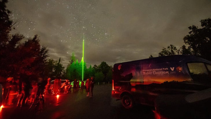 A group at night at Voyageurs National Park, enjoying a star party, with a national-park support van parked on the premises.