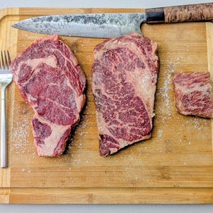 Three american wagyu steaks on a cutting board.