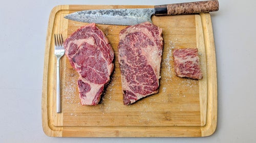 Three american wagyu steaks on a cutting board.