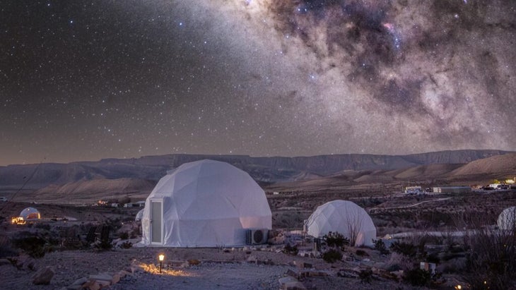 The dome accommodations at the Summit at Big Bend, Texas, are located in a wide area of desert, with a starry sky above.