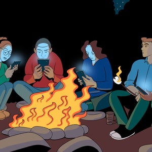 friends looking at their phones around a campfire