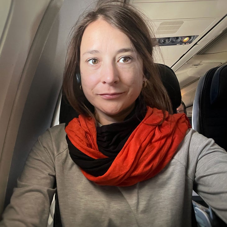 woman wearing a sleeping bag liner as an infinity scarf on an airplane