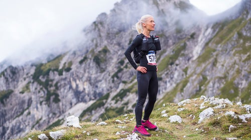 Woman at the start of a running up the mountain competition with a start number. Trail running race.