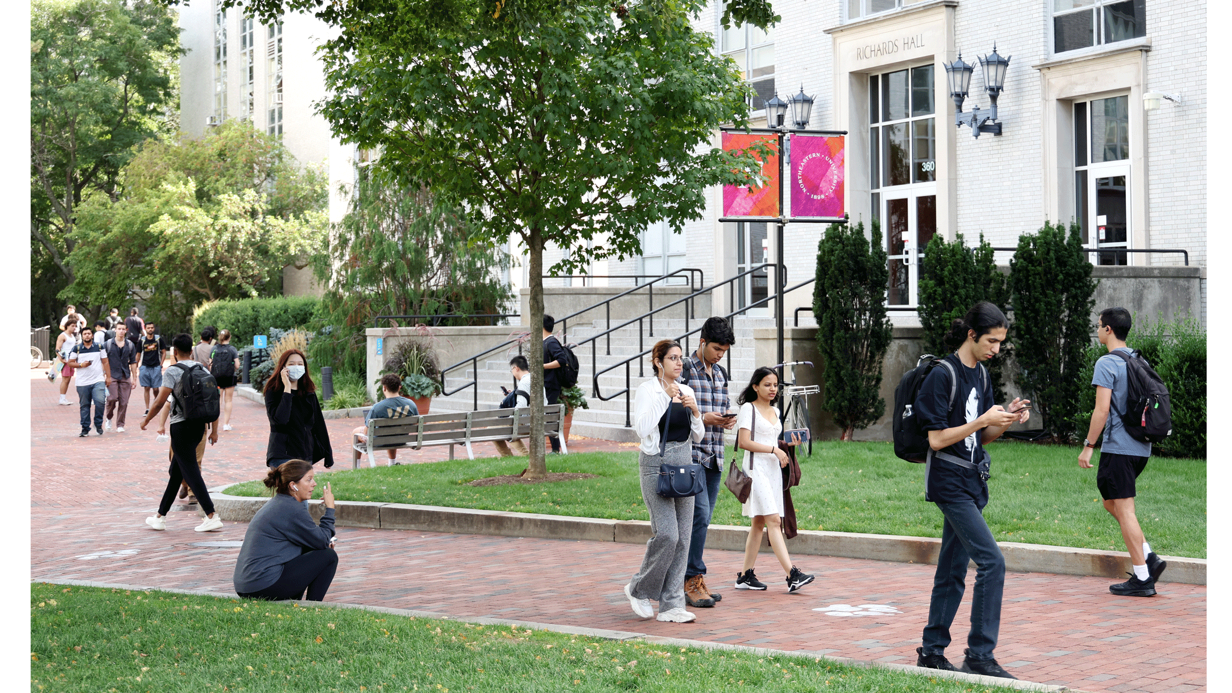 College campus with students walking across the lawn and the brick paths