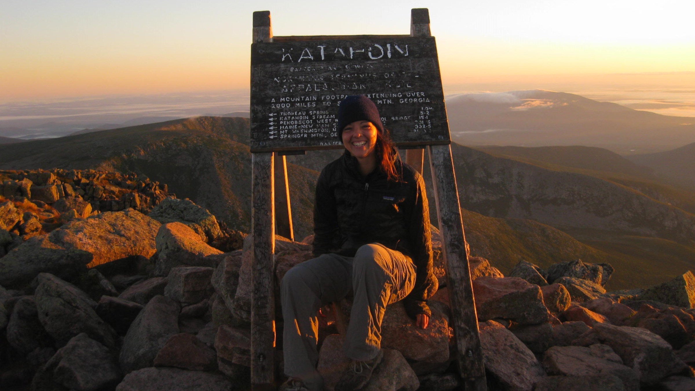 a hiker on top of Katahdin at sunset