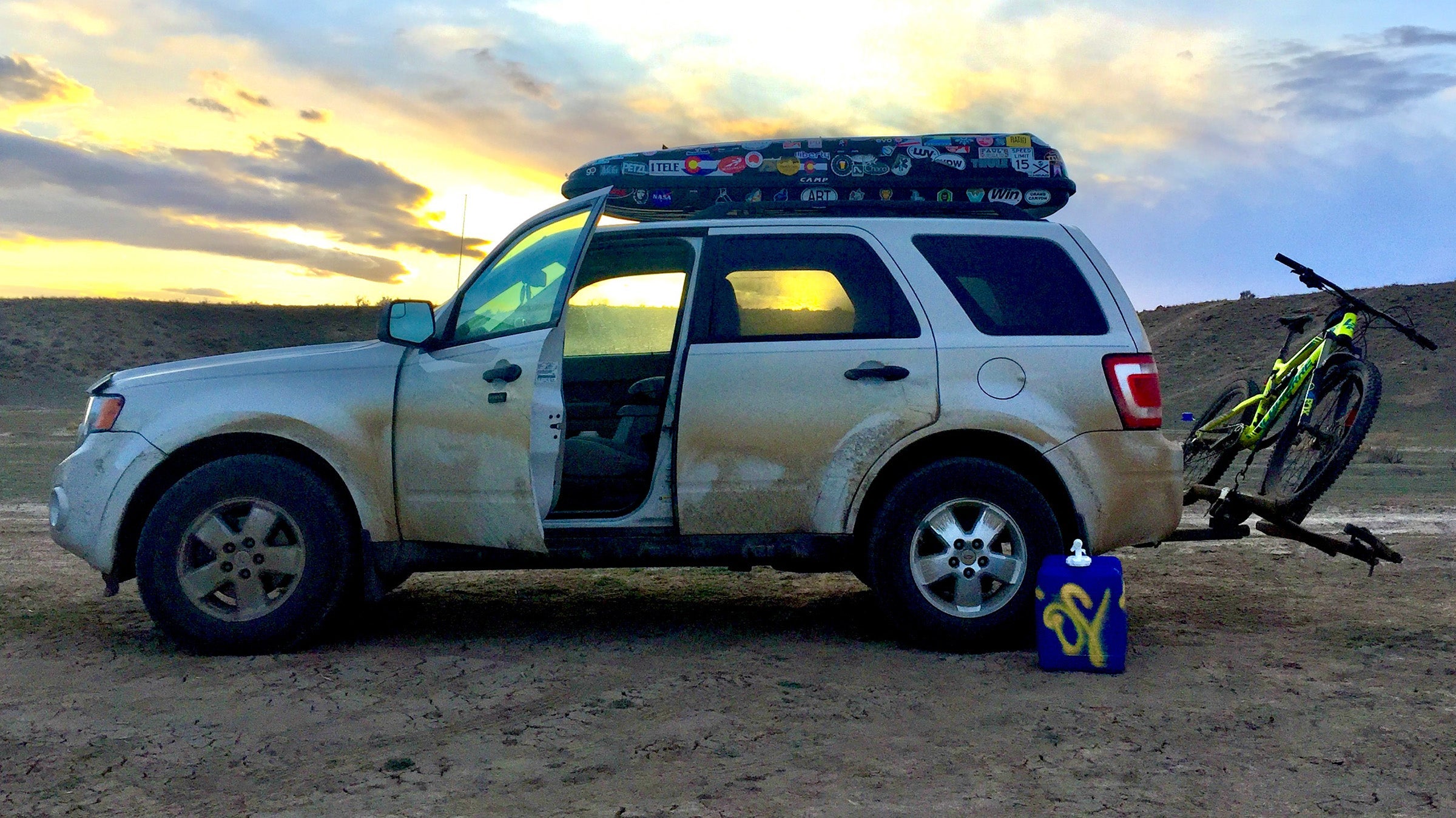 White SUV parked in desert with roof box and bike carrier