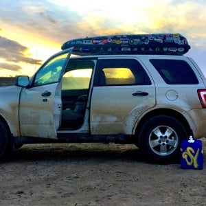 White SUV parked in desert with roof box and bike carrier