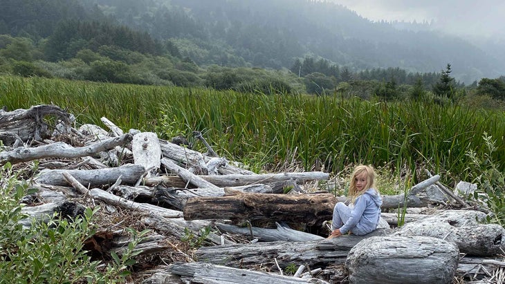 The author's daughter sitting at the beach during their camping trip.