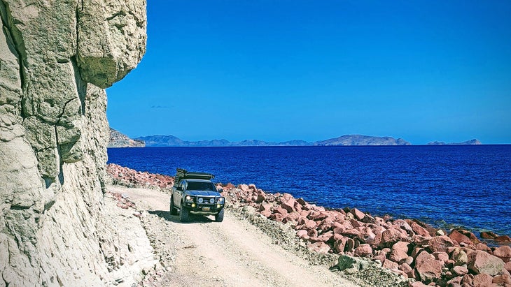 A truck on a dirt road by the sea. Overlanding