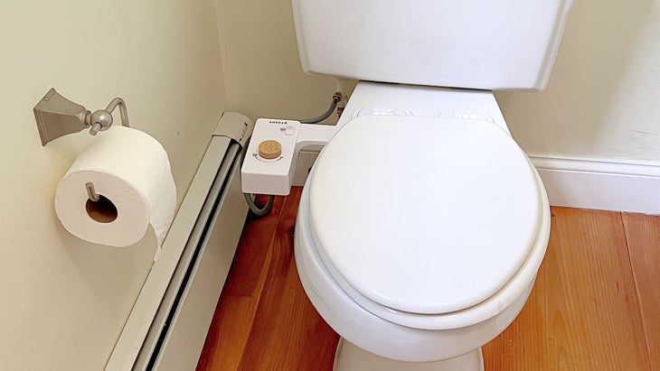 A white toilet with a Tushy Classic bidet installed