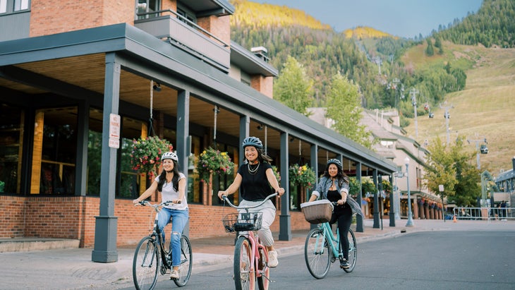 three women riding bikes through Aspen in summer