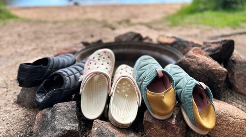 three pairs of camp shoes around a fire pit