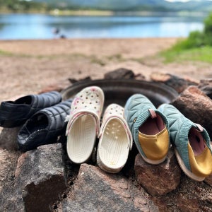 three pairs of camp shoes around a fire pit