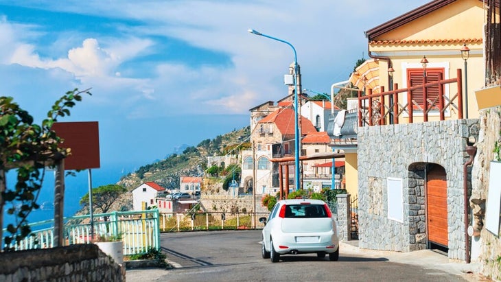 A car drives toward a town on the coast of Italy