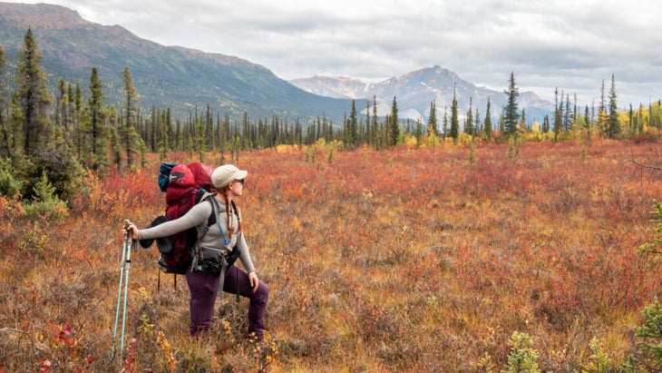 The author, carrying a big backpack and trekking poles, sets off across the Alaskan backcountry on a hike.