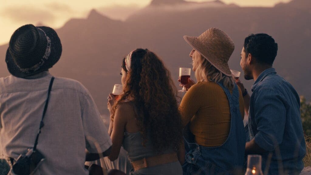 Four people looking out at the mountains, each with a glass of wine in hand