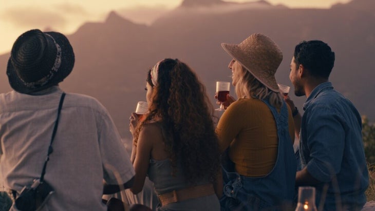 Four people looking out at the mountains, each with a glass of wine in hand