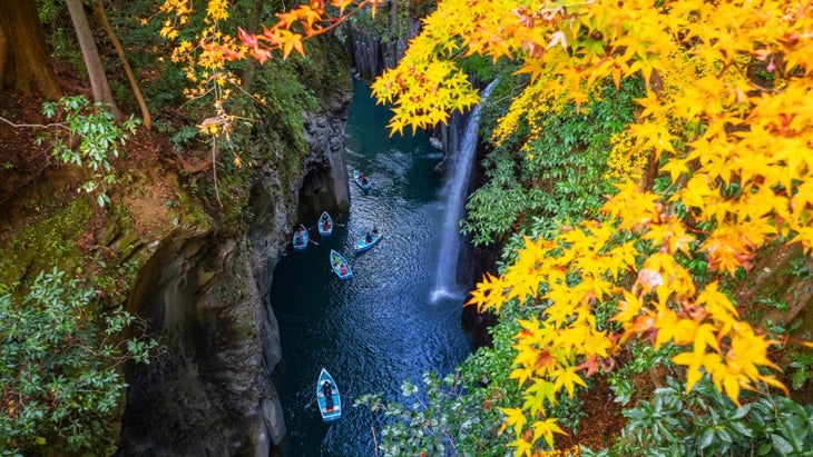 A group of cancers paddle past a waterfall while making their way down Japan’s Takachiho Gorge amid the fall foliage.